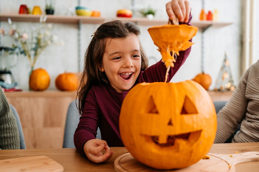 Un niño levanta la parte superior de una calabaza que acaba de tallar, ilustrando las frases graciosas y tiernas de calabaza de Hofmann para pies de foto de Halloween en Instagram.