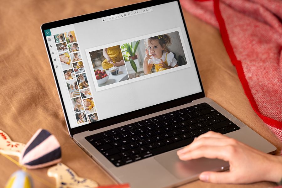 Manos frente a un portátil que muestra el editor online de Hofmann, para mostrar lo fácil que es crear un álbum de fotos como regalo de Navidad personalizado, para ilustrar el calendario de Hofmann para crear un regalo personalizado con fotos.