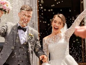 Una pareja feliz el día de su boda, cubierta de confeti, capturando un momento lleno de alegría que inspira ideas de regalos de aniversario de boda por años.