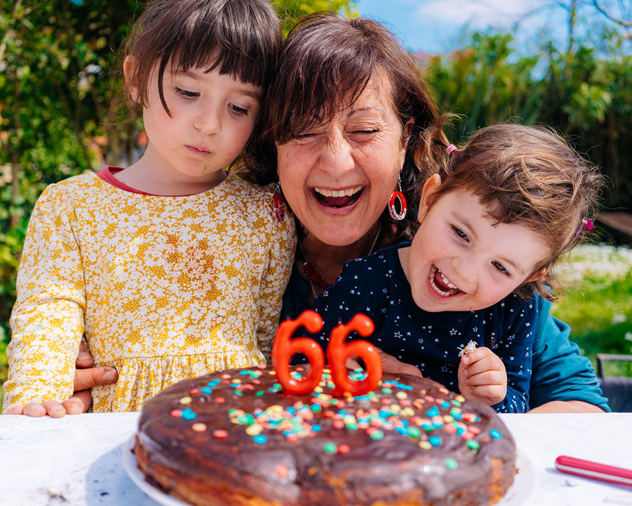 Abuela se divierte con sus dos nietos apagando velas de cumpleaños.