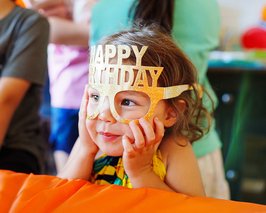 Niña con una máscara dorada de "Feliz cumpleaños".
