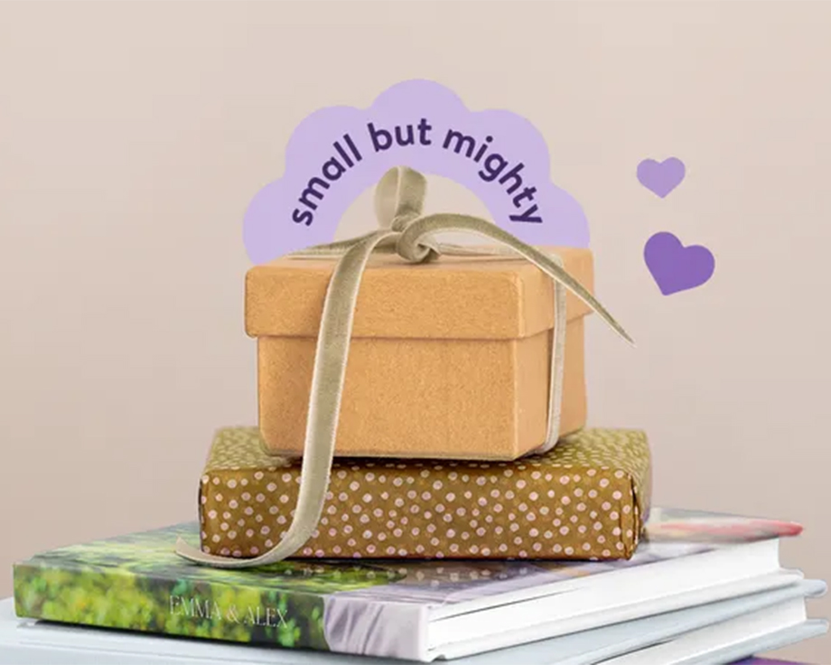 Una pila de fotolibros de Hofmann con un regalo envuelto encima, como inspiración para pequeños regalos personalizados e ideas de regalos con fotos.