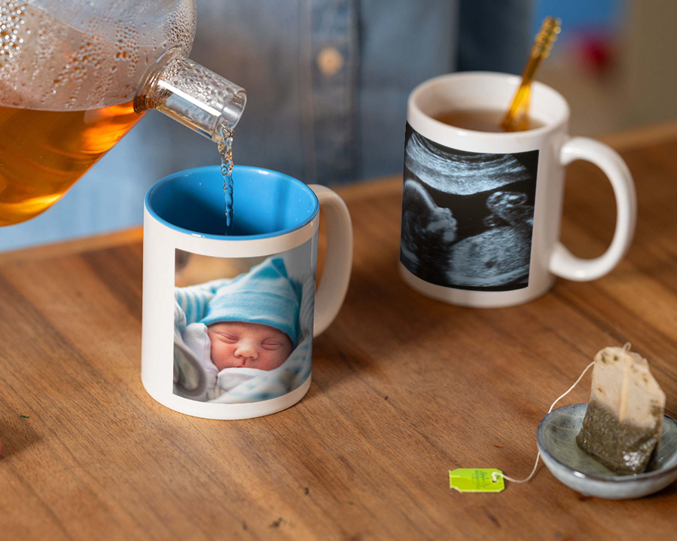 Té servido en una taza personalizada con fotos de un recién nacido junto a otra taza con una ecografía.