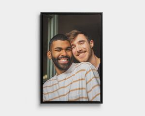 Retrato en lienzo enmarcado en negro de dos hombres sonrientes.